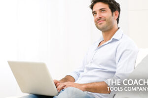Coach considering email list on sofa with laptop