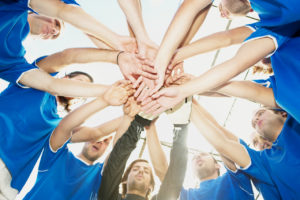 Group Coaching Approaches - shown by football team linking hands