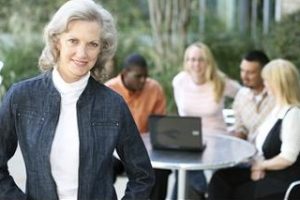 Group and Team Coaching shown by woman in front of table of people doing an exercise