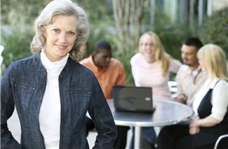 Group and Team Coaching shown by woman in front of table of people doing an exercise