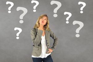 Woman wondering what the best coaching questions to ask are? Surrounded by question marks