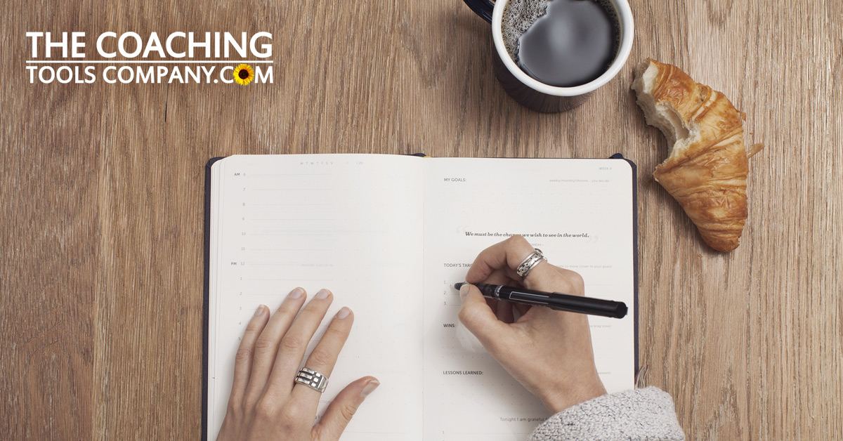 Hands journaling around leadership questions at desk with coffee