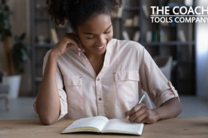 Smiling coach at desk writing in journal